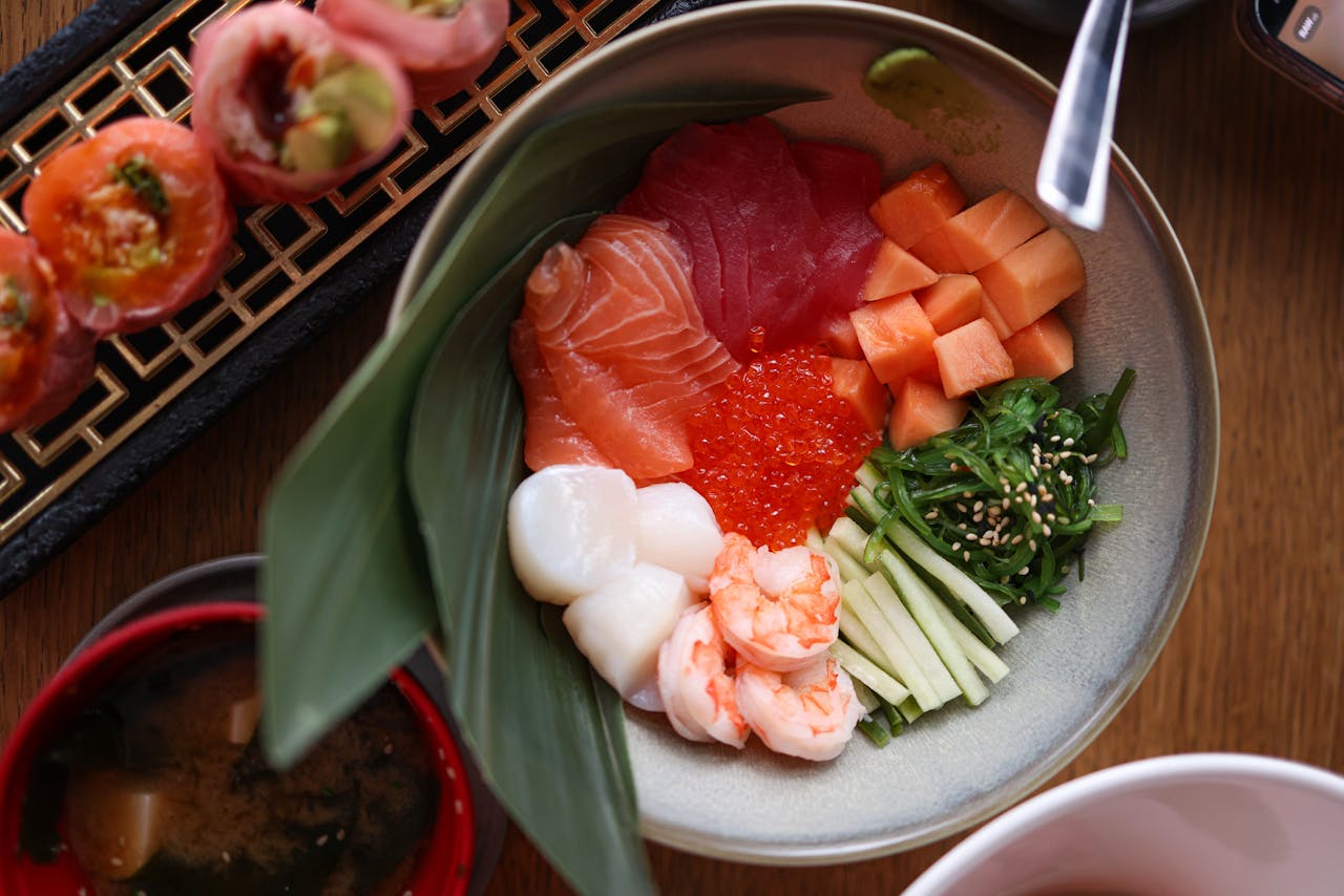 services-02 Vibrant Japanese seafood bowl featuring sashimi, shrimp, seaweed, and fresh vegetables.