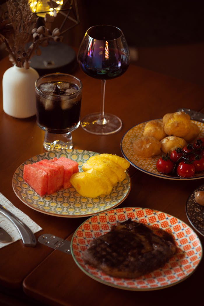 about-04 Elegant dinner setting with gourmet steak and vibrant fruit display, offering a cozy and intimate dining experience.